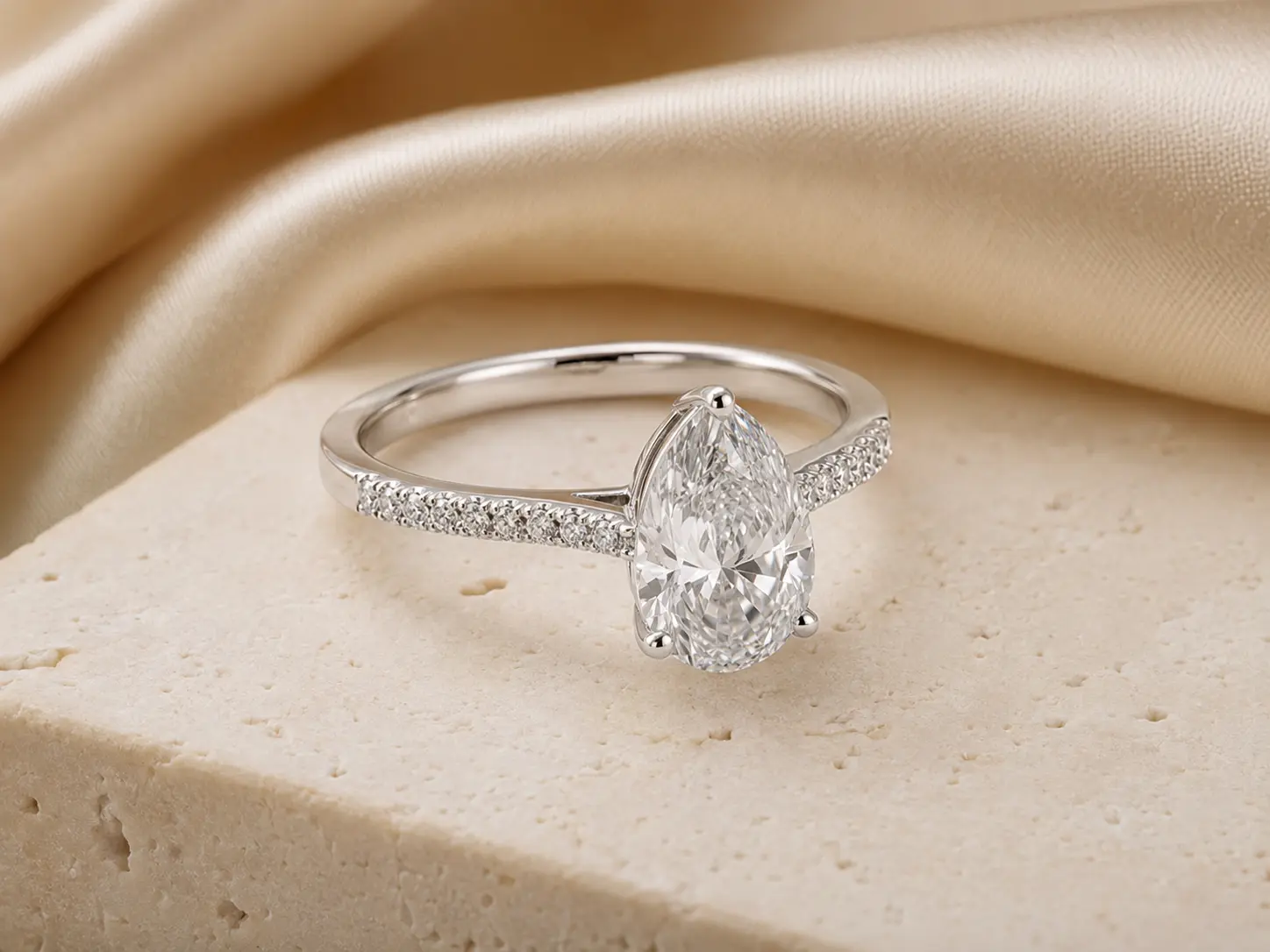 Verlobungsring in Weißgold mit tropfenförmigem Diamanten und Pavébesatz