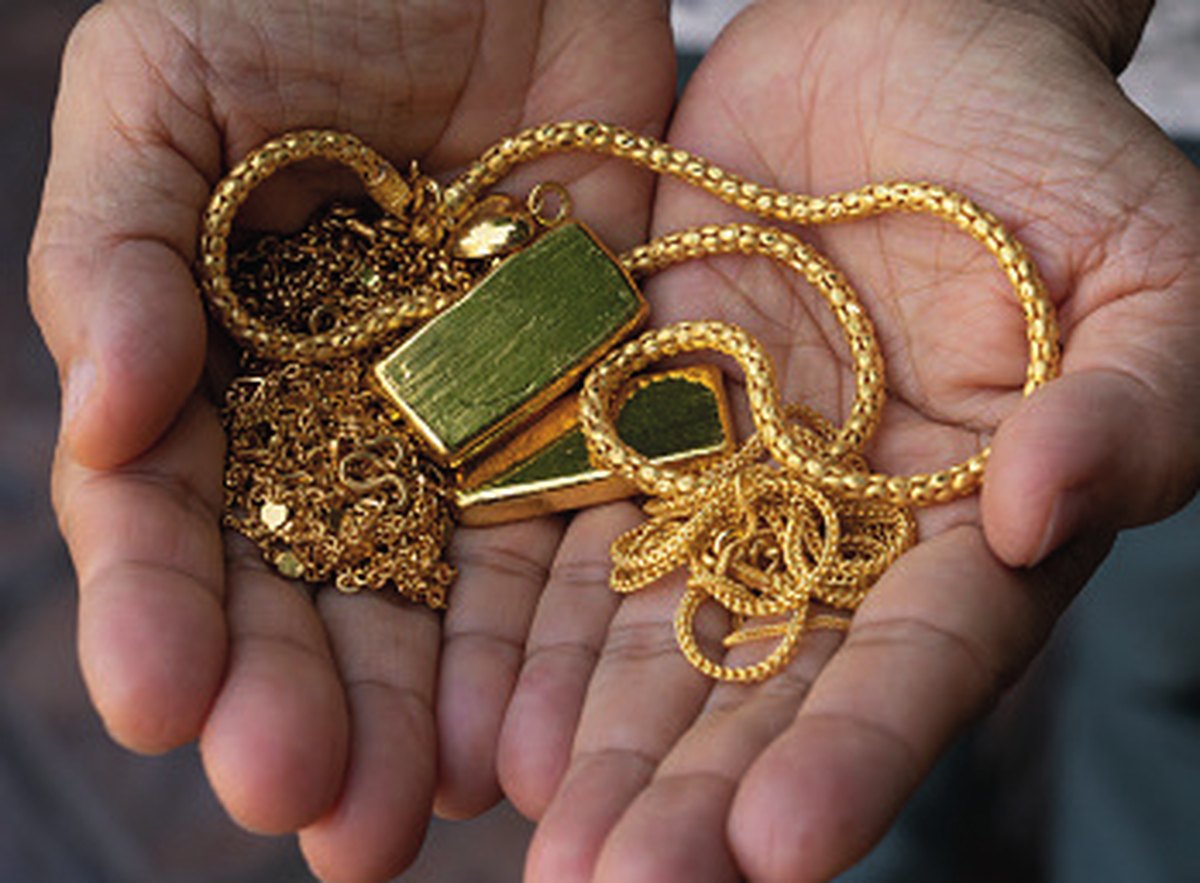 Hände halten Goldschmuck, Goldketten und einen Goldbarren beim Goldankauf von Juwelier EGGER in Kufstein