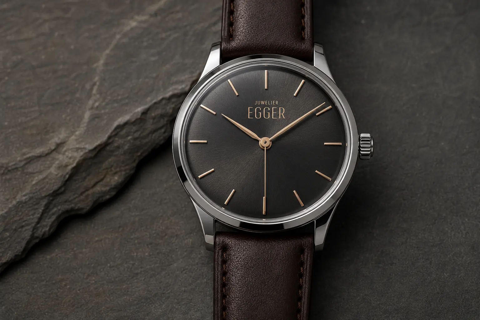Elegante Armbanduhr mit Krone auf 3 Uhr und goldfarbenem Juwelier-EGGER-Logo unter 12 Uhr